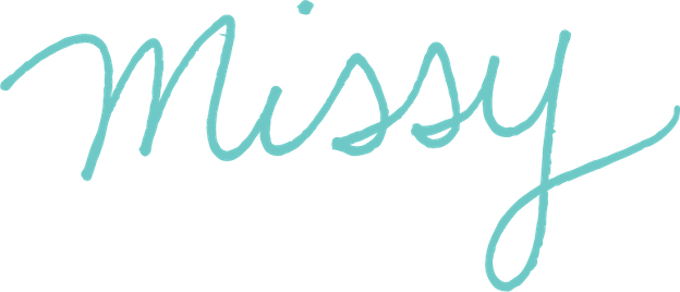 "Missy" is a written in handwriting in a blue-green color on a transparent background. It is her signature.