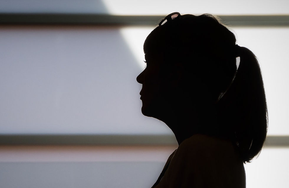 A woman in silhouette looks to the left with sunglasses on her head.