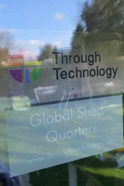 A sign on a garden office saying "Through Technology Global Shedquarters"