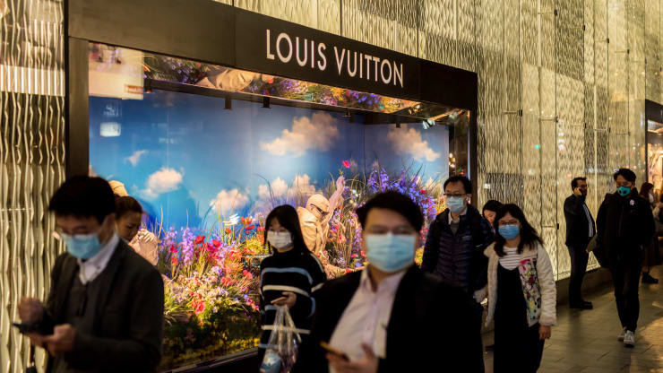 Pedestres em frente a Louis Vuitton usando máscaras na reabertura do mercado depois durante a pandemia