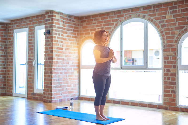 Woman in yoga studio standing with hands folded to chest