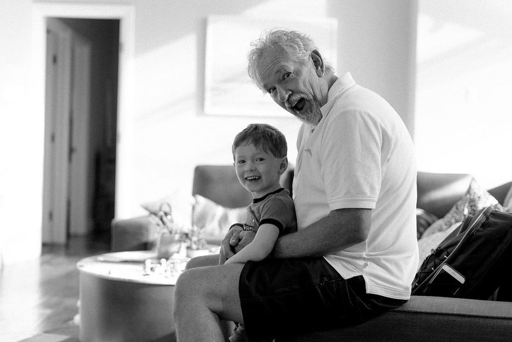 Portrait of a young boy and his grandpa, sitting on the couch and smiling
