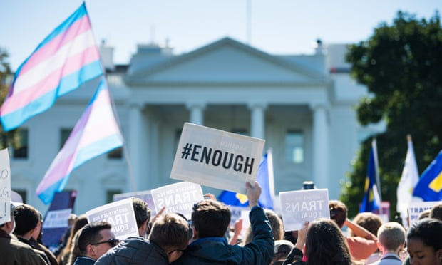 Protestors stand outside the White House holding the transgender flag and a poster that says #enough.