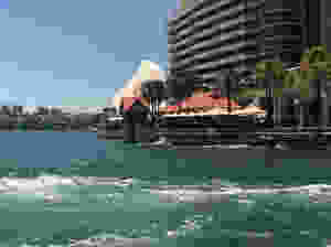 Circular Quay partial view from ferry leaving the harbor showing building, waterside restaurant, Sydney Opera House and city skyline in background