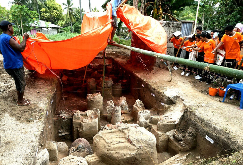 Tenaga lokal menutup Situs Lambanapu menggunakan terpal begitu hujan mulai turun, Senin (29/4/2019) di Desa Lambanapu, Kecamatan Kambera, Kabupaten Sumba Timur, Nusa Tenggara Timur. Kotak galian di situs berusia sekitar 2000 tahun ini akhirnya ditimbun kembali oleh Pusat Penelitian Arkeologi Nasional untuk menjaga keamanan artefak dan kerangka-kerangka manusia di dalamnya. Penutupan ini sifatnya sementara dan uatu saat, kotak galian bisa dibuka kembali.