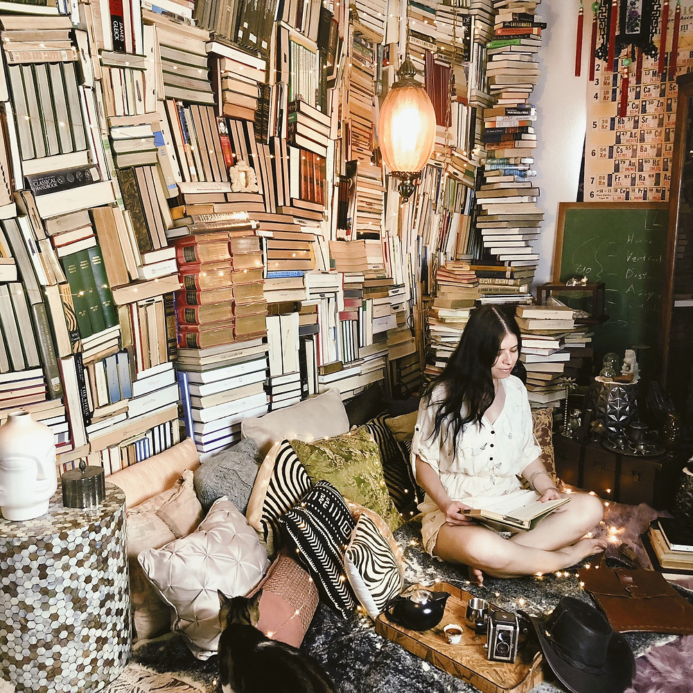 Midimalism Maximalism Person Reading In Front Of Bookwall Bookporn Book Spiral Column Swag Lamp Mini Strings Of Lights Cat Green Chalkboard Decor And Lifestyle Advice Blog Fabsolutely.Co Make Your Life Awesome