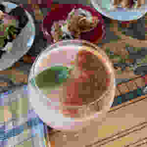 Bubbly light pink drink with cinnamon and a lone basil leaf