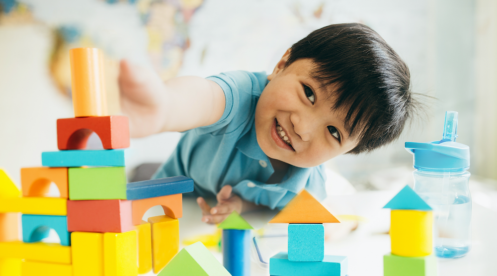A preschooler playing with wooden blocks - an educational toy.