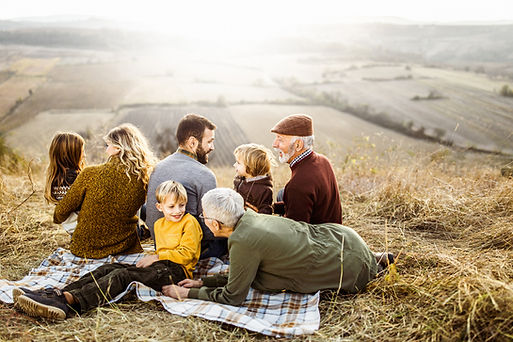 Multi-generational family sitting on a hill overlooking fields