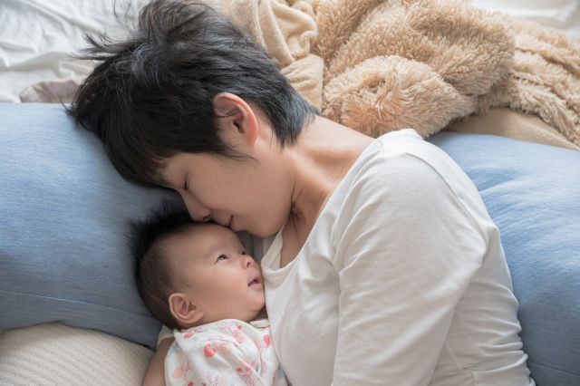 赤ちゃんと添い寝する母親