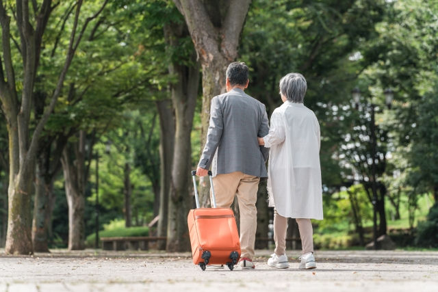 スーツケースを持ちながら歩く老夫婦