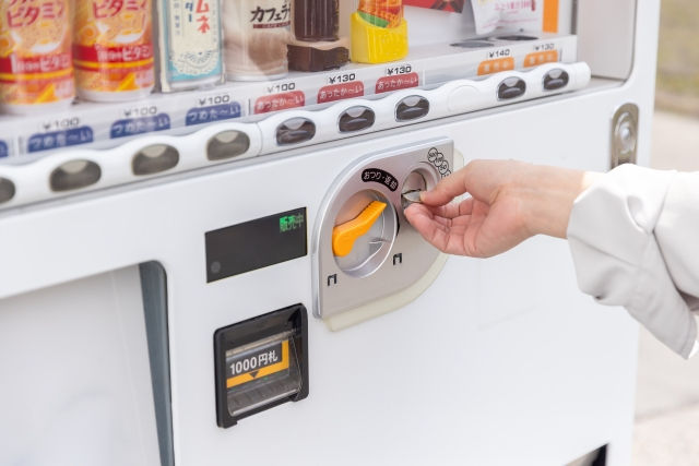 自販機におかねを入れる女性