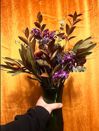 a person is holding a vase filled with purple flowers