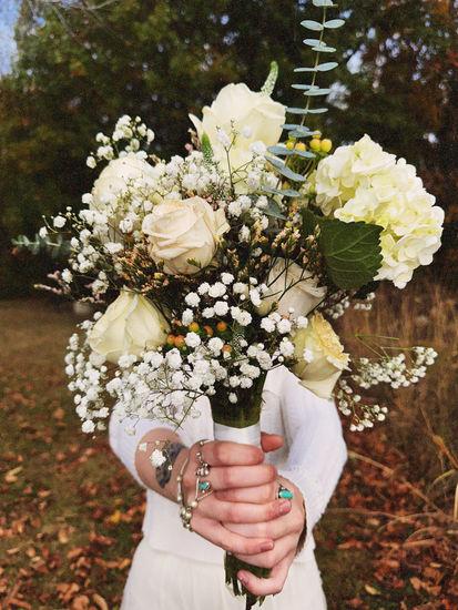 a woman holding a bouquet of white flowers with baby 's breath