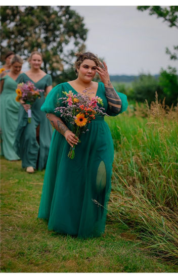 a woman in a green dress holds a bouquet of flowers