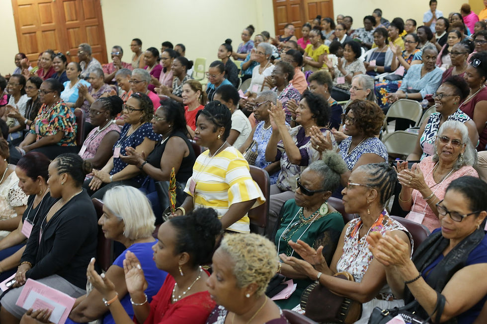 Large group of women seated in an auditorium, clapping and smiling during a conference