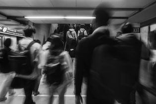 People walking away from the camera at a Toronto subway station, captured in black and white with slow shutter speed.