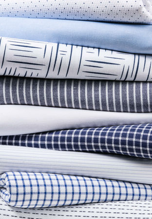 Close-up of stacked bedsheets in Toronto, Canada, showing different styles in the same neutral tone.