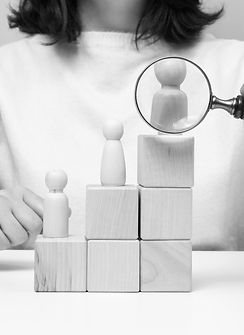 woman-holding-a-magnifying-glass-and-wooden-men-on-2025-03-24-04-47-10-utc.jpg