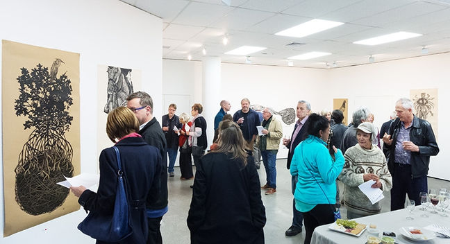 Art gallery opening reception with guests enjoying refreshments and artwork.