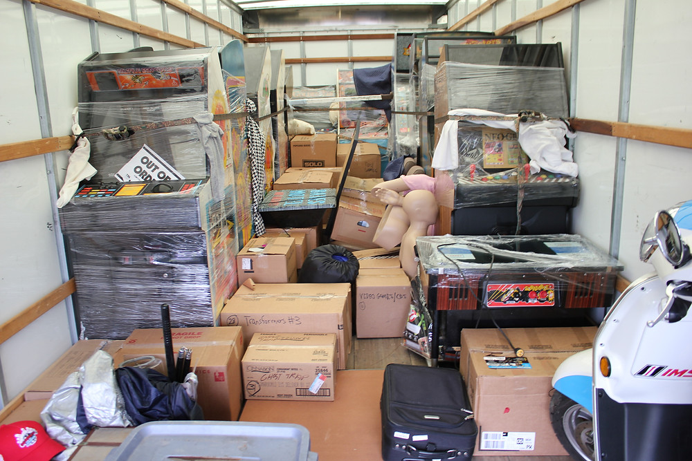 Penske moving truck filled with arcade games, boxes and a Kymco scooter