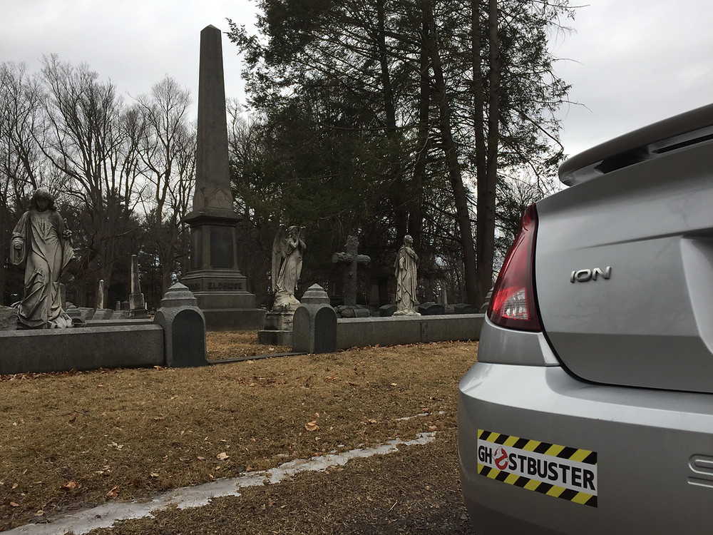 Ghostbuster bumper sticker on a Saturn Ion in a cemetery.