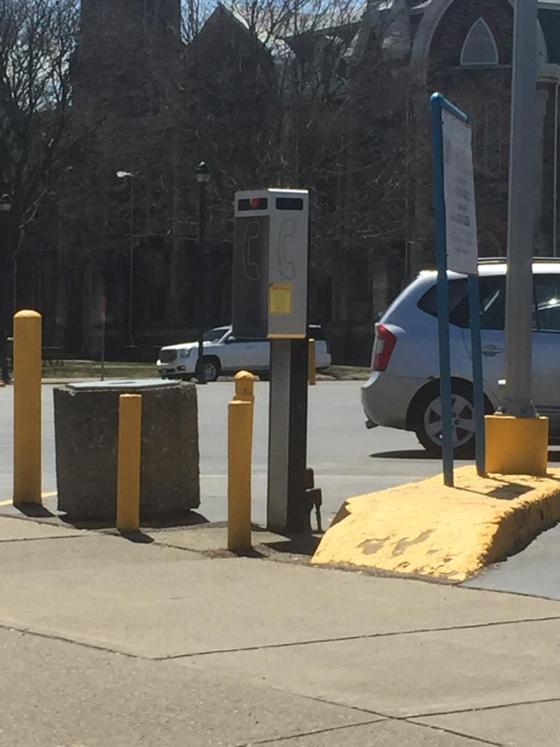 Empty payphone kisok in a parking lot.