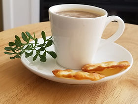 A cup of Ethiopian coffee capuccino with crispy snack and garden Rue