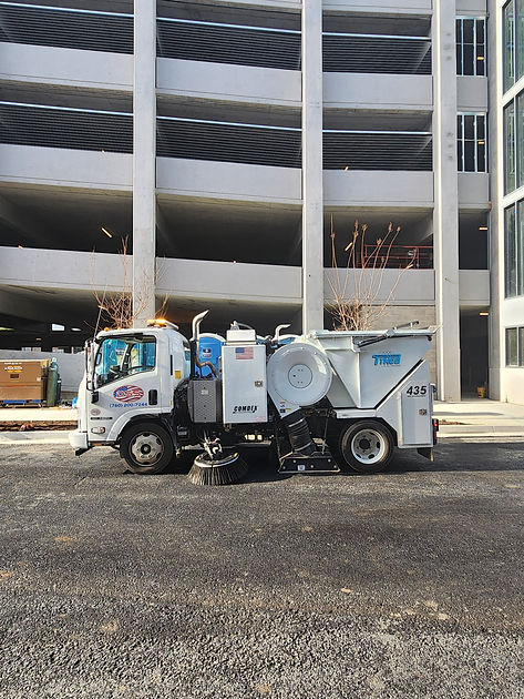 DSS white Street Sweeping truck outside of a commercial building