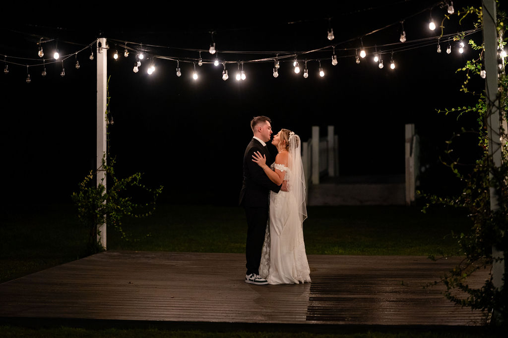 Bride and groom sharing a private dance beneath outdoor string lights at night