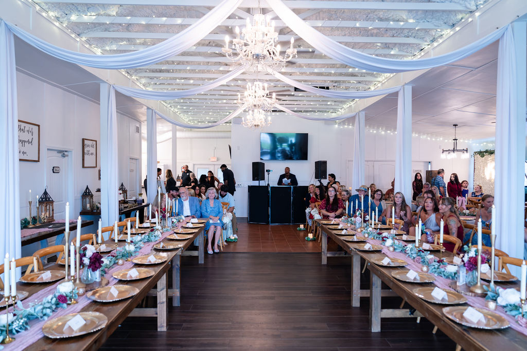 Bright reception hall with long decorated tables and draped ceiling fabric