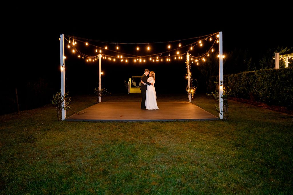 Wide view of a private last dance beneath outdoor string lights