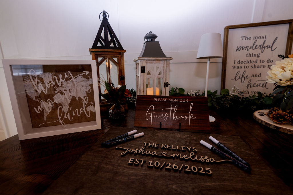 Wedding guestbook table with pens, lanterns and framed signs