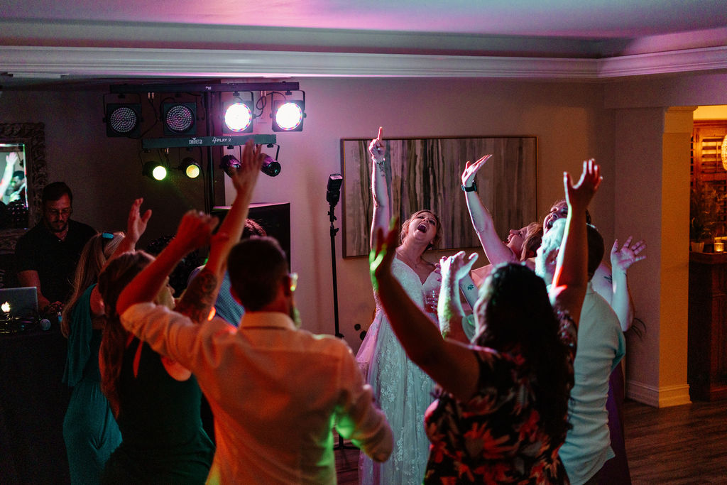 Wedding guests dancing under colorful reception lights