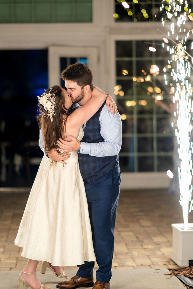 Bride and groom kissing beside bright wedding sparkler fountains