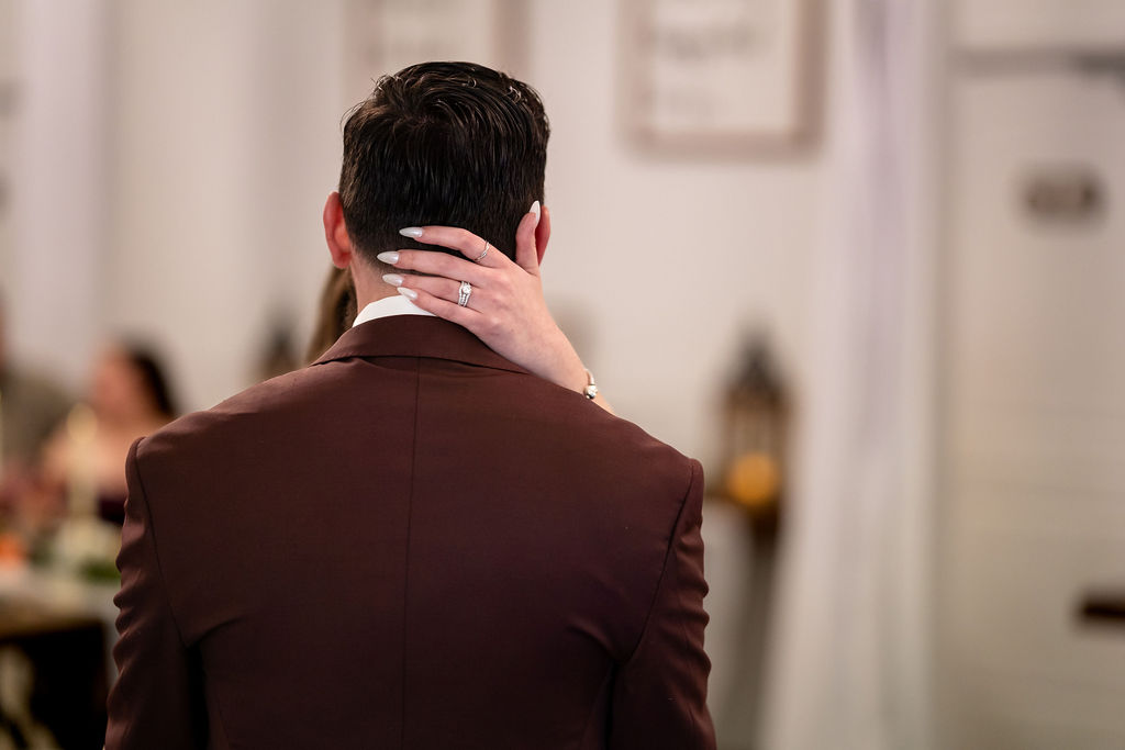 Close-up of the bride’s hands around the groom during their dance