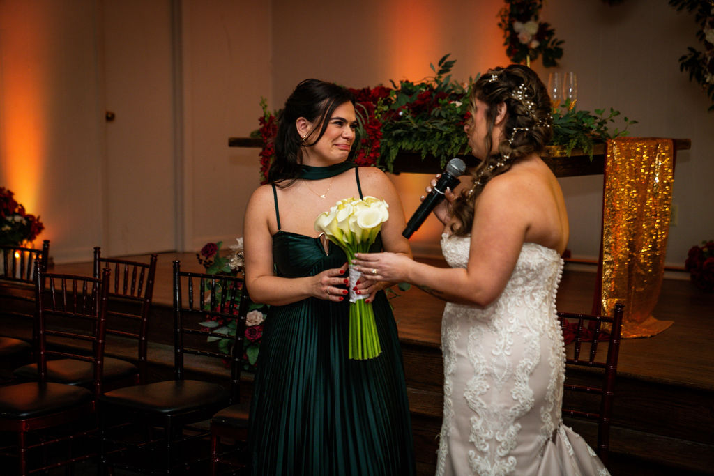Bride presenting a bouquet to a woman in a green gown