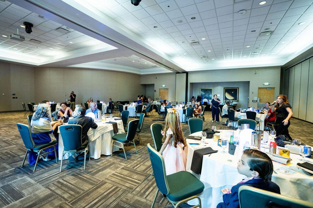 Wide view of reception tables and guests in a bright ballroom
