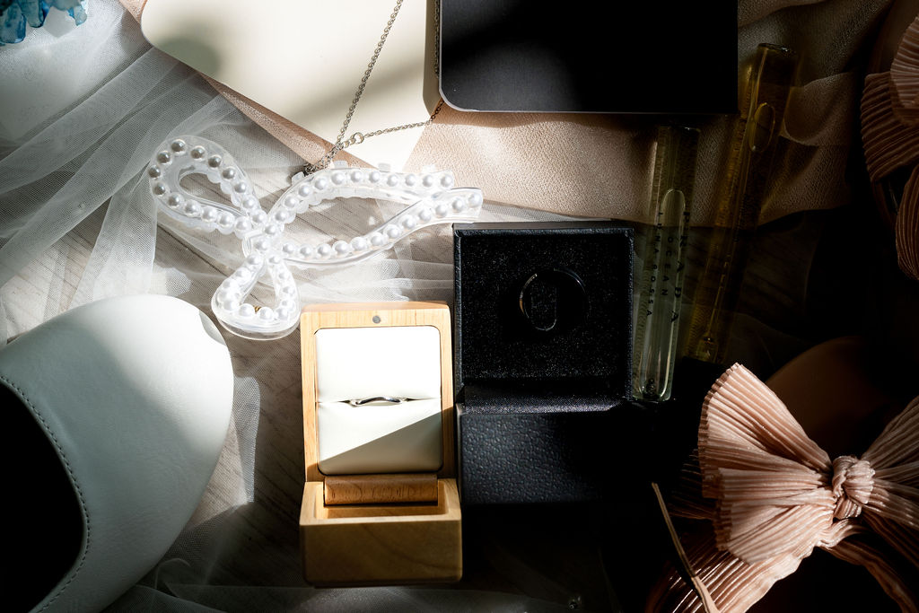 Wedding rings in boxes with bridal shoes and a pearl bow