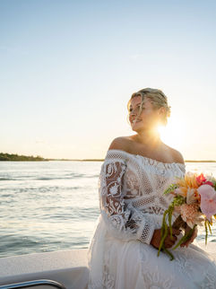 Bride holding bouquet near water during golden hour wedding portrait