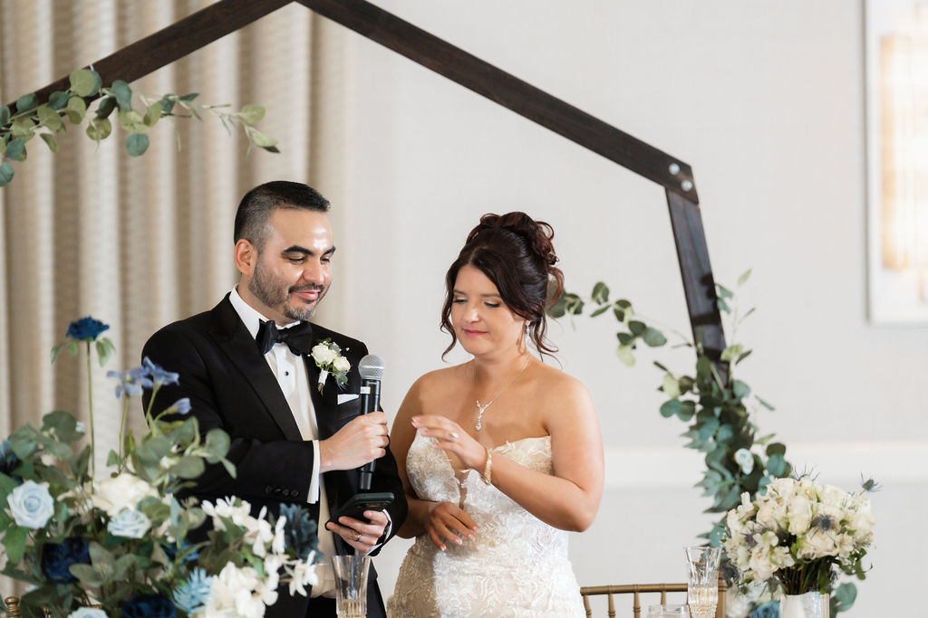 Bride and groom giving a toast together beneath a floral arch