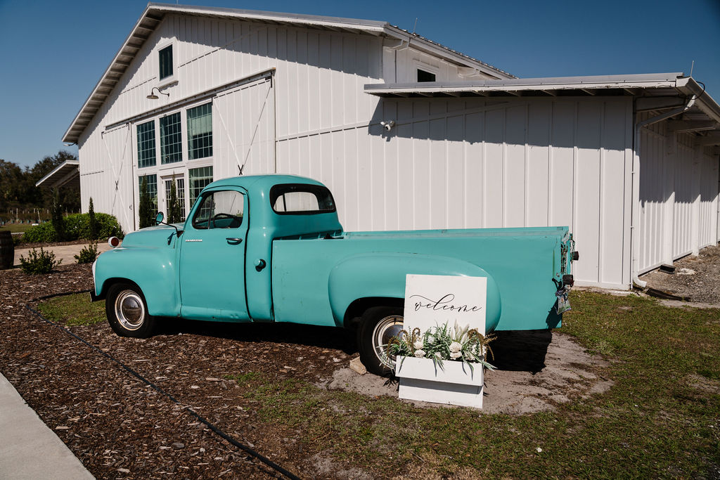 Vintage turquoise pickup truck beside a white wedding barn