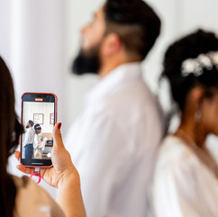 Guest recording bride and groom during wedding ceremony using smartphone