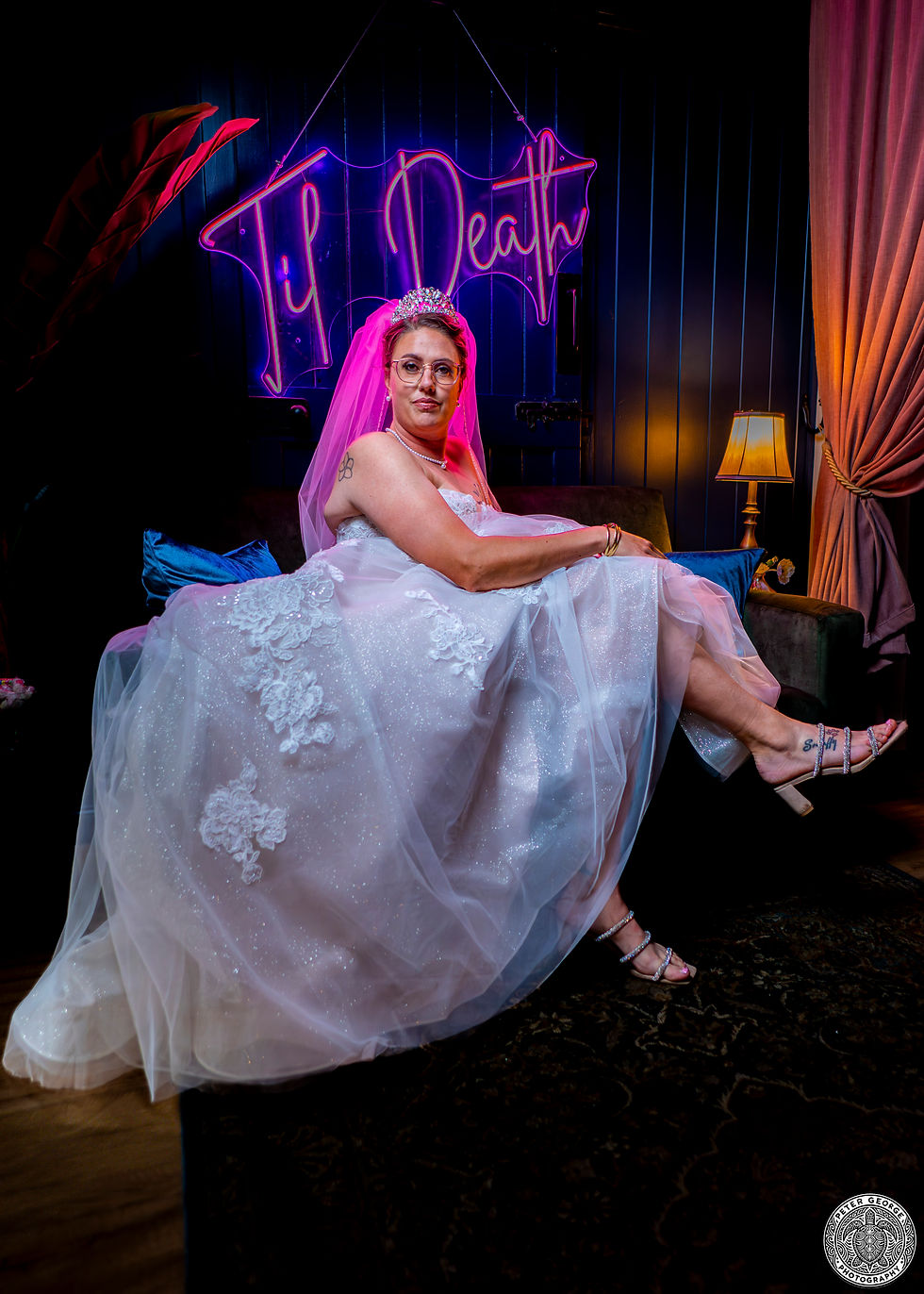 Bride in white gown under 'Til Death' neon sign.
