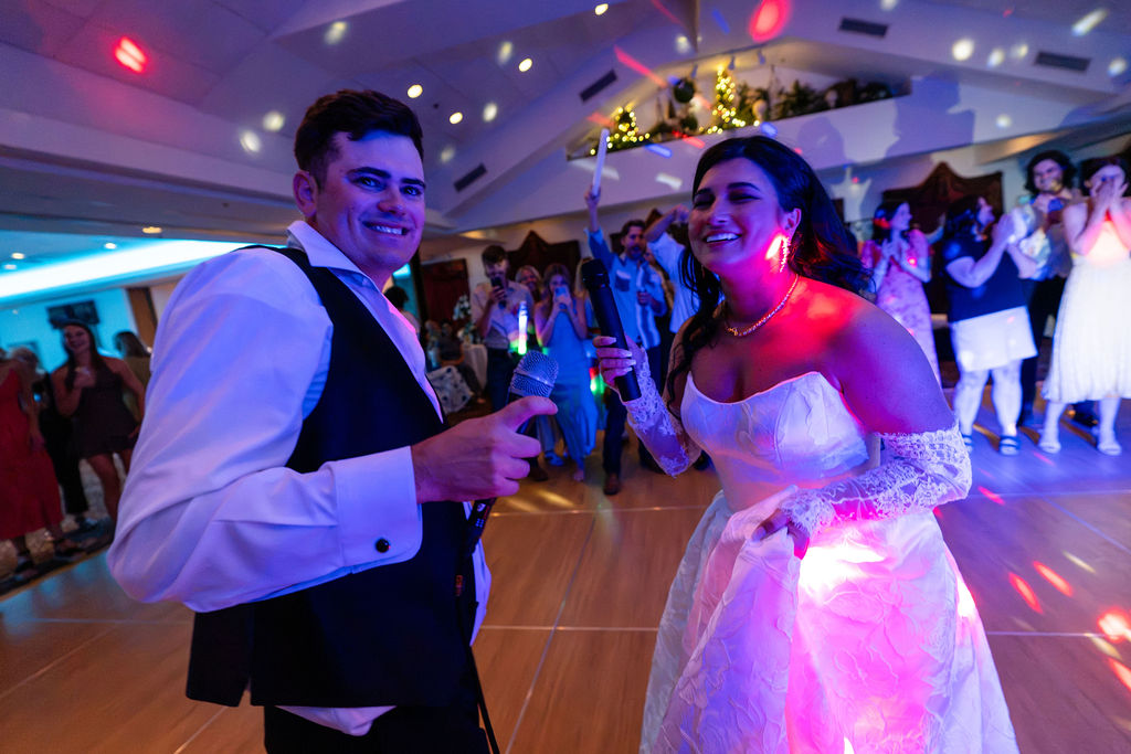Bride and groom celebrating together under colorful reception lights