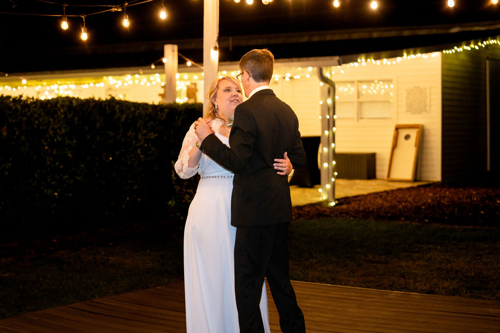 Newlyweds dancing at night beside a warmly lit barn