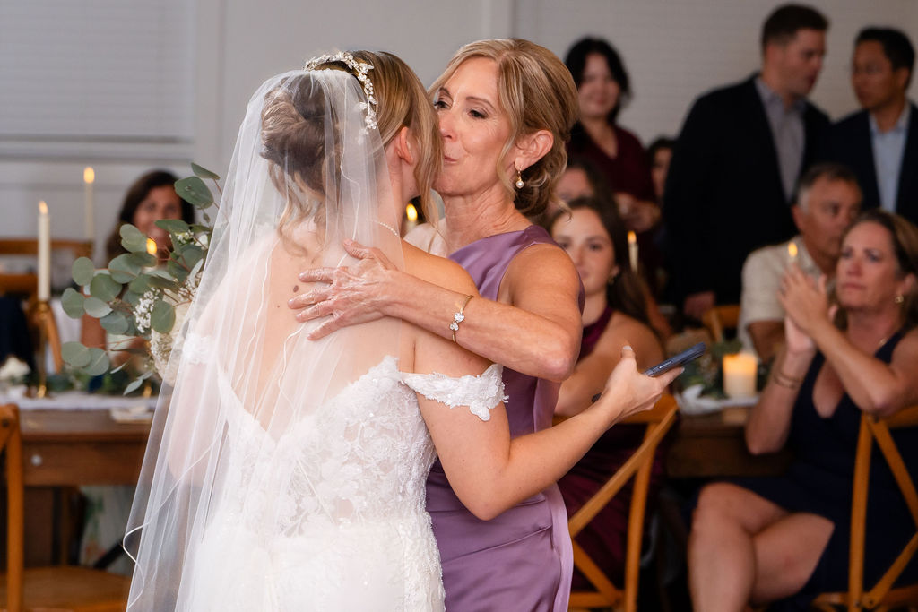 Bride embracing a woman in a purple gown at the reception