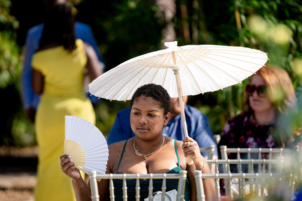 Wedding guest holding a white parasol and ceremony program