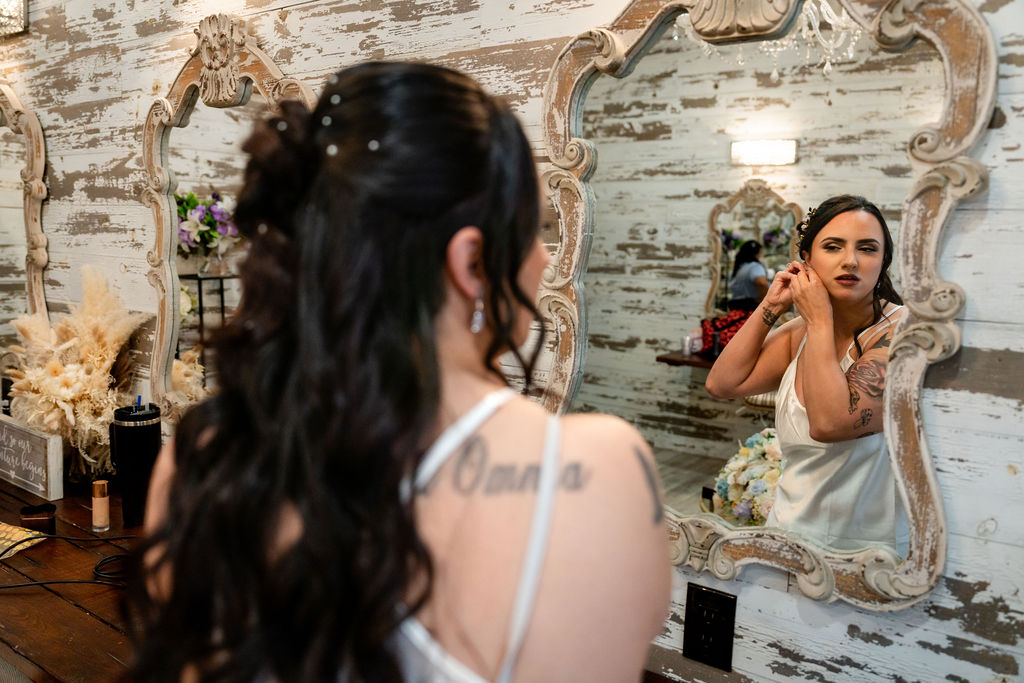 Bride checking her makeup in an ornate dressing-room mirror