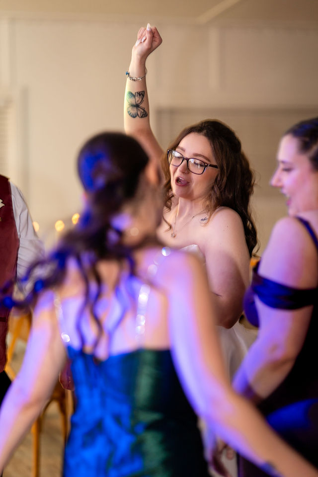 Bride and guests dancing under colorful reception lights